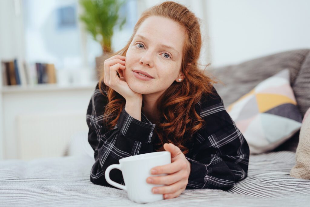 Woman relaxing at home holding a coffee mug, conveying calm and comfort after selling a mortgage note