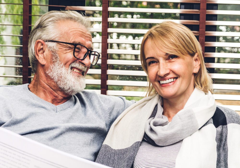 Senior couple smiling while reviewing paperwork at home after deciding to sell a land contract for a lump sum of cash