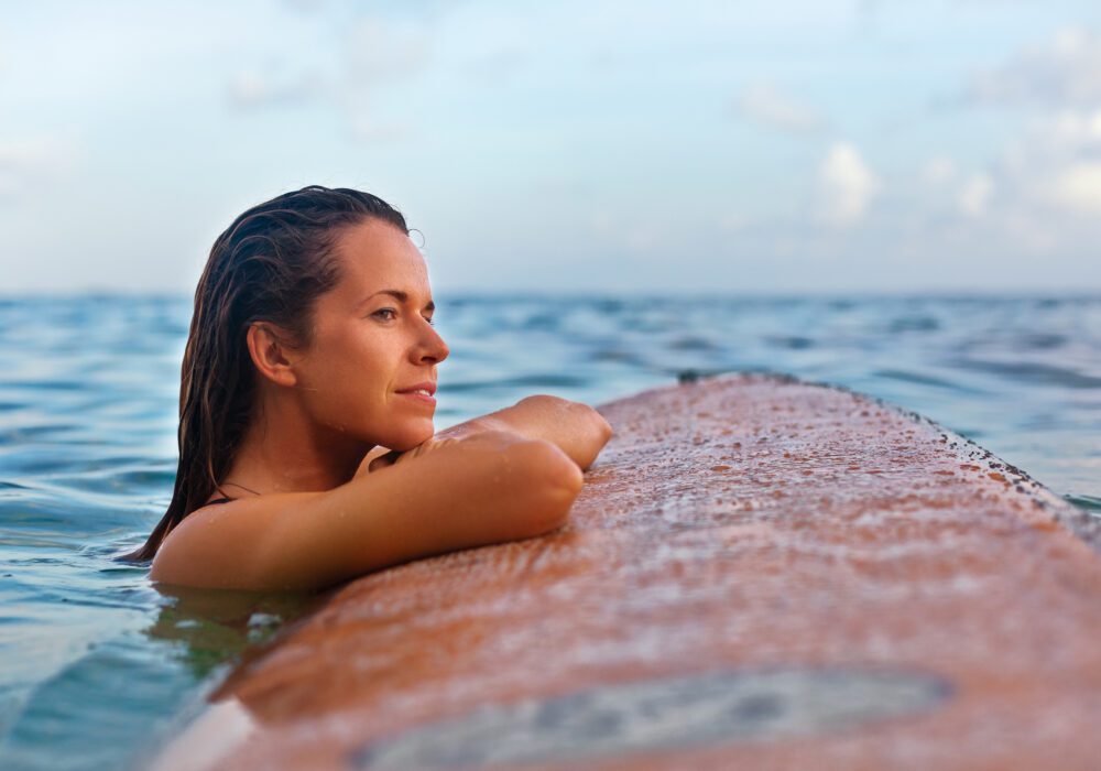best mortgage note buyer – woman resting peacefully on a surfboard in calm ocean water, representing the freedom of choosing the right note buyer