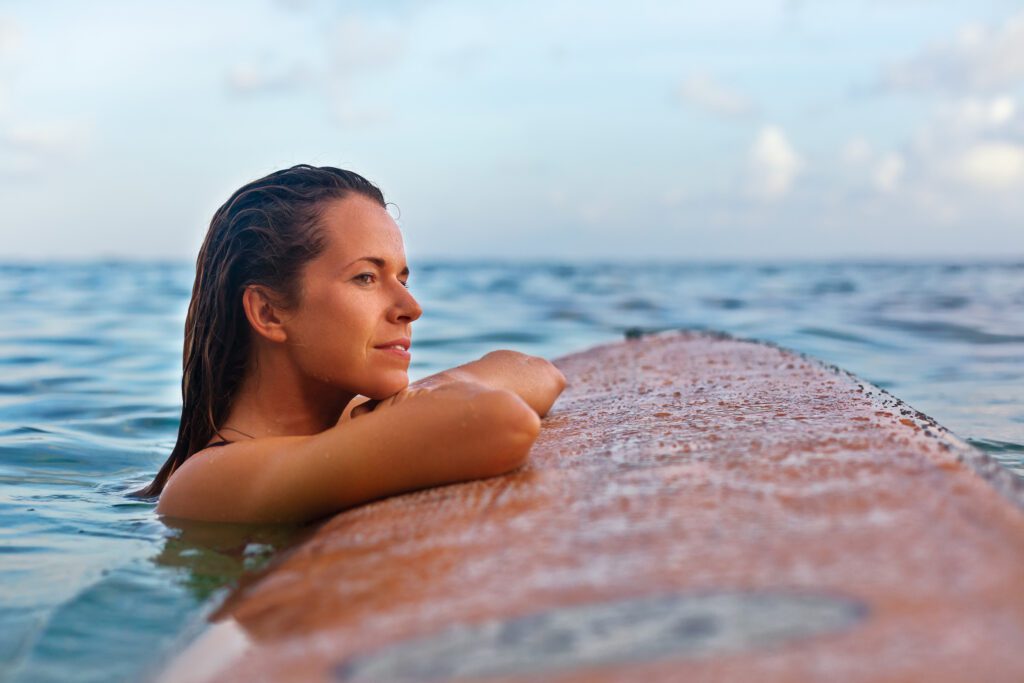 best mortgage note buyer – woman resting peacefully on a surfboard in calm ocean water, representing the freedom of choosing the right note buyer