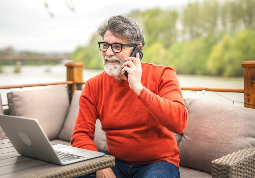 man smiling on outdoor patio while talking with best mortgage note buyers by phone