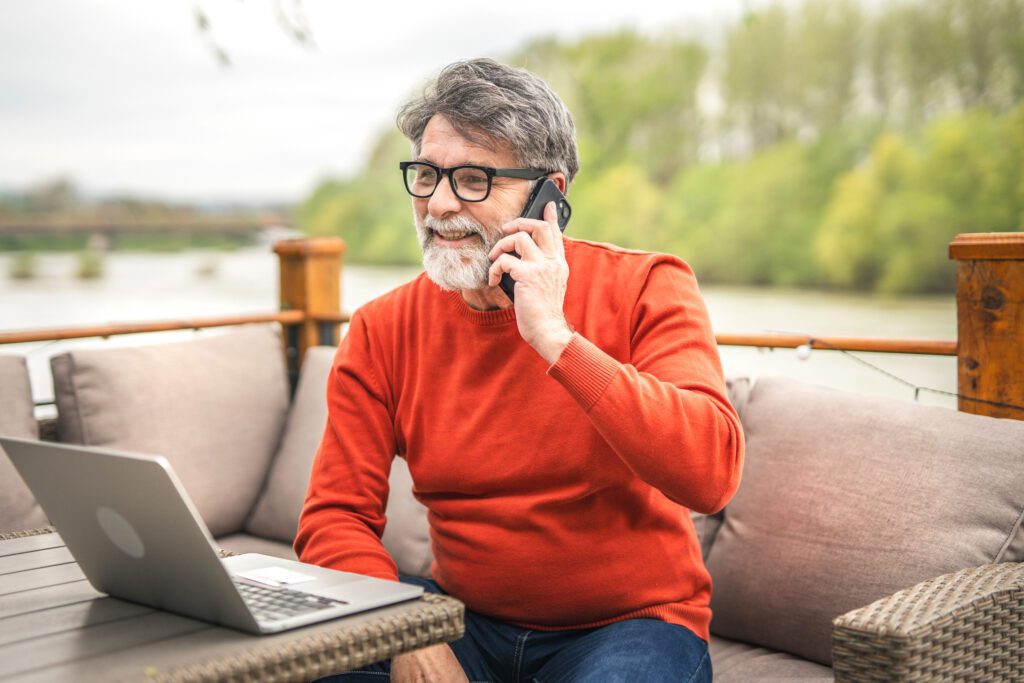 man smiling on outdoor patio while talking with best mortgage note buyers by phone